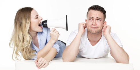 Eine Frau schreit einem Mann durch ein Megaphon ins Ohr. Sie streiten sich.